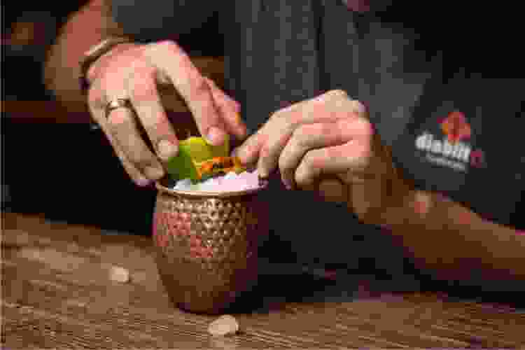 bartender zesting lime over a cocktail