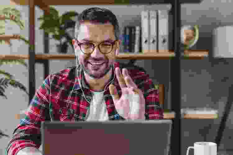 man waving to online friends during a virtual game night