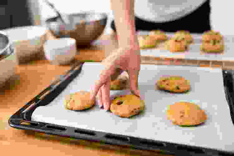 hand placing cookie dough on baking sheet