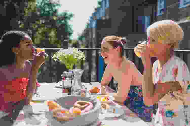 three women chatting over outdoor brunch