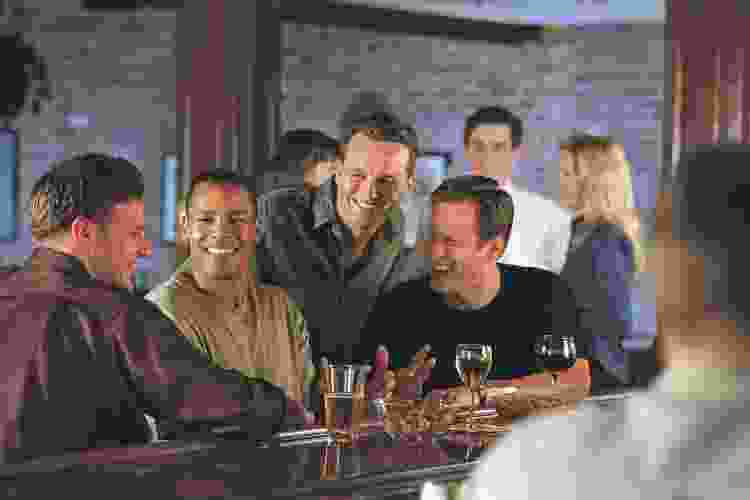 group of guys drinking beer and chatting at a bar