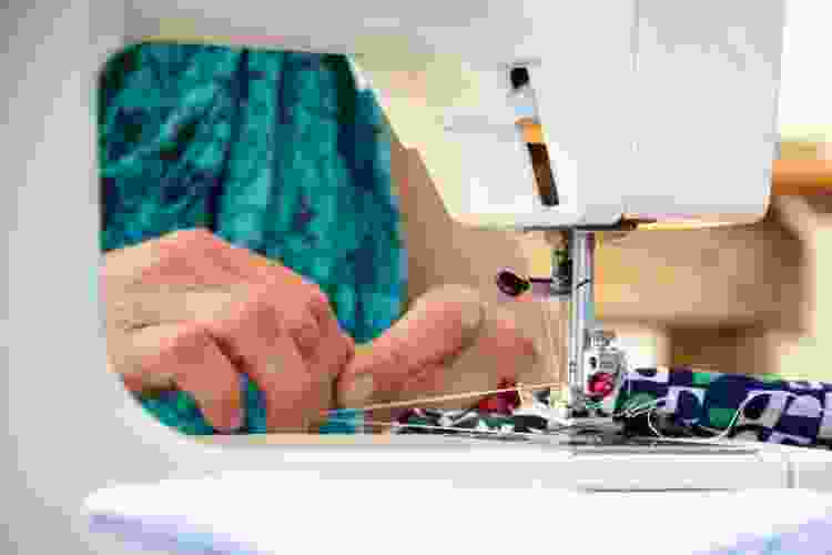 hands on fabric under sewing machine