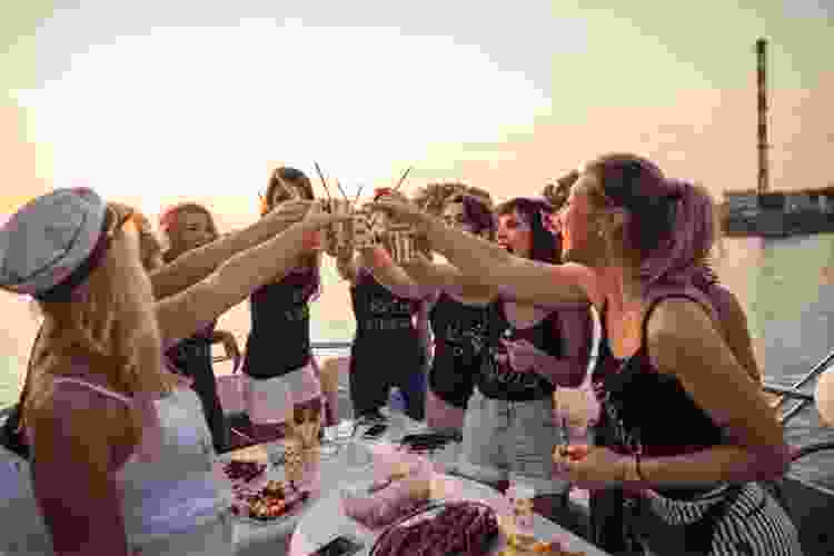 women cheers drinks on boat for bachelorette party