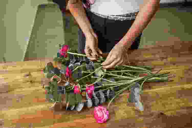 hands arranging bouquet of pink flowers