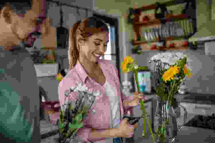 happy couple arranging flowers together in kitchen