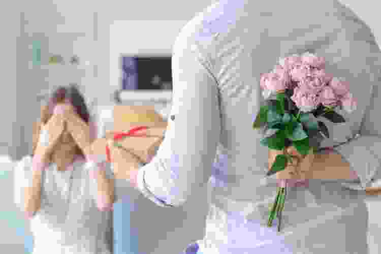 man hiding bouquet of flowers behind his back