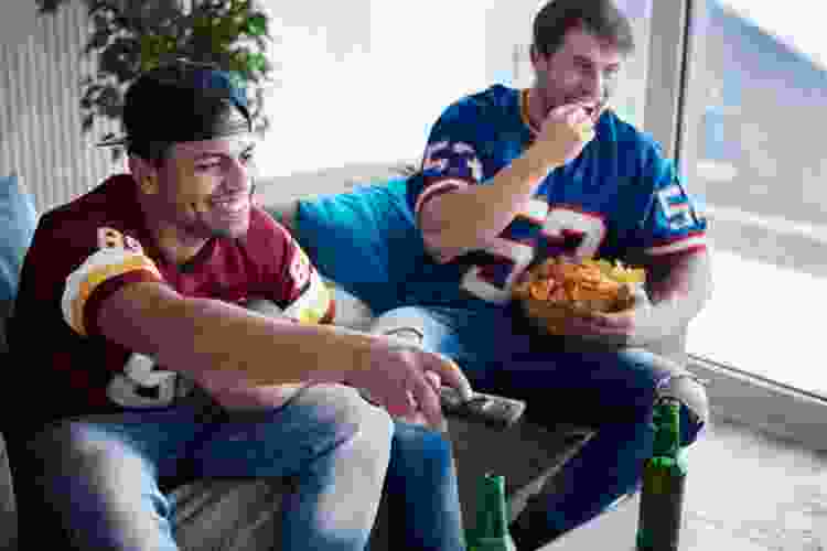 two people in jerseys watching sports with beer