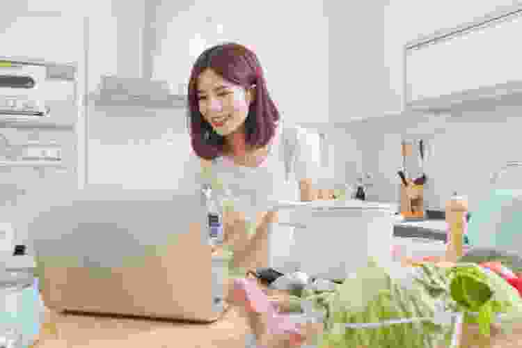 making food in kitchen while using laptop