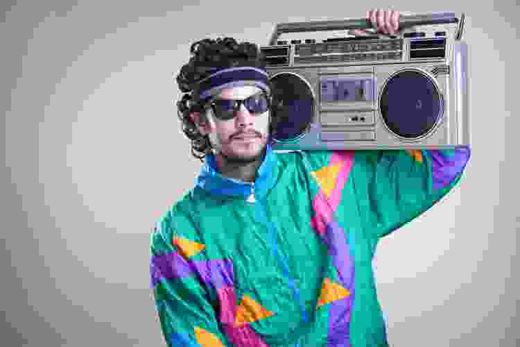 person with boombox on shoulder dressed in 80s jacket and sunglasses