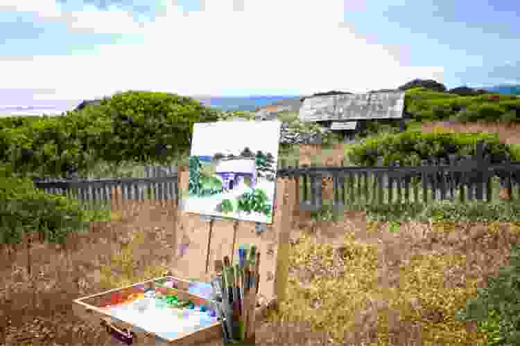 canvas on easel painting in countryside with house