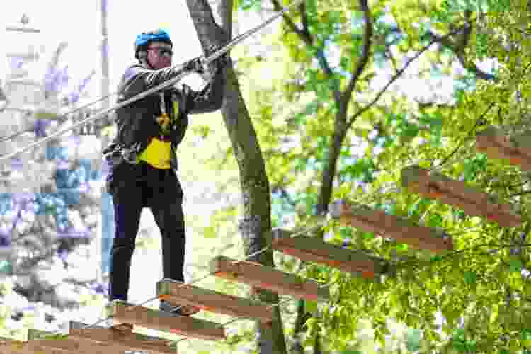 man walking on ladder ropes course