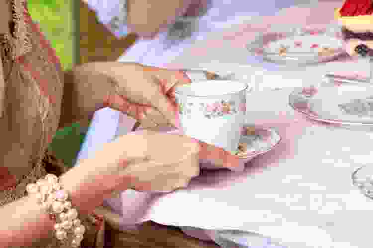 woman holding teacup at afternoon high tea party