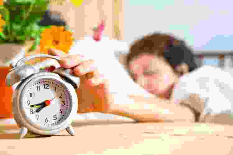 person snoozing vintage alarm clock