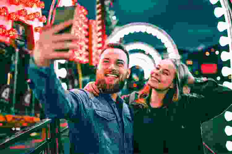 two friends taking selfie under the lights at an amusement park