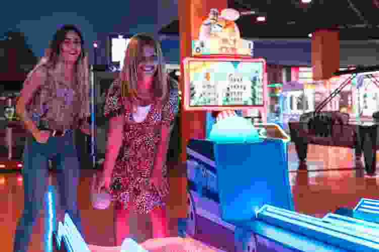 young women playing skee ball at arcade