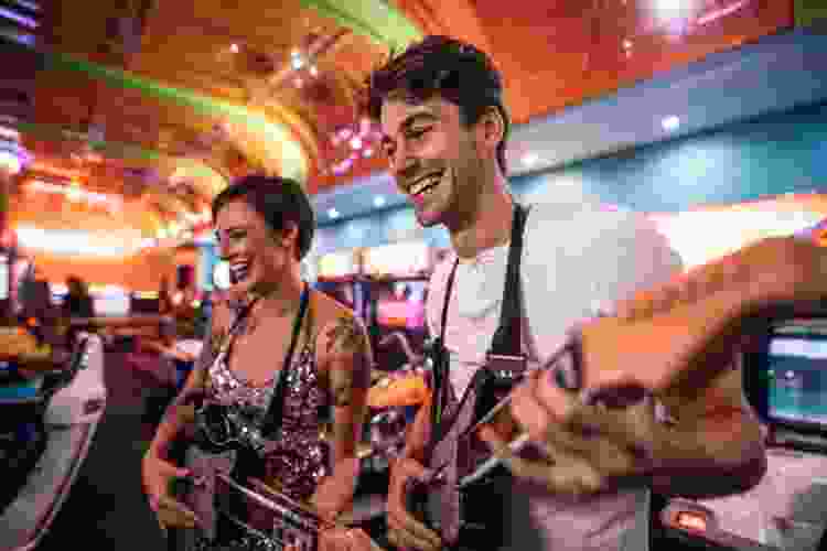 couple playing guitar hero together at an arcade