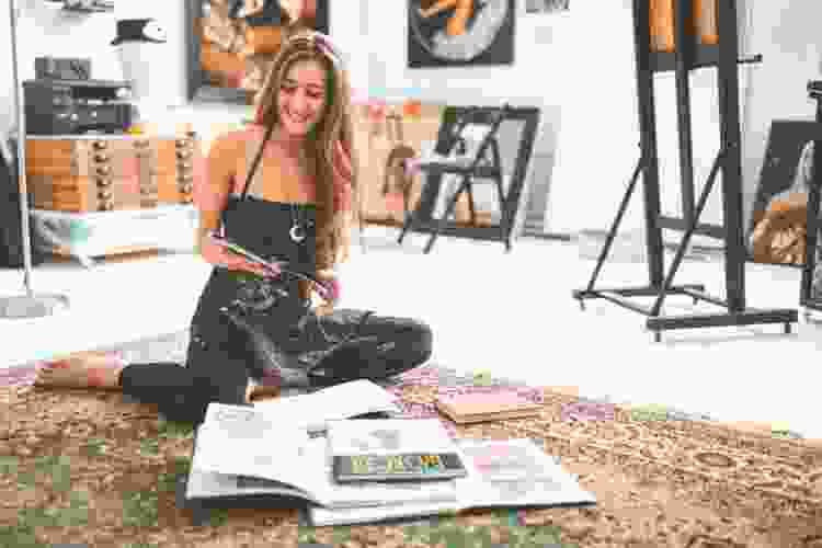 artist on floor with pile of books