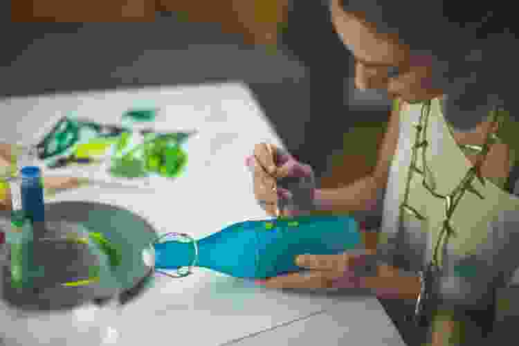 woman painting blue glass jar