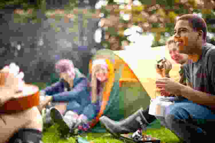 teens camping out with tents and bonfire in backyard