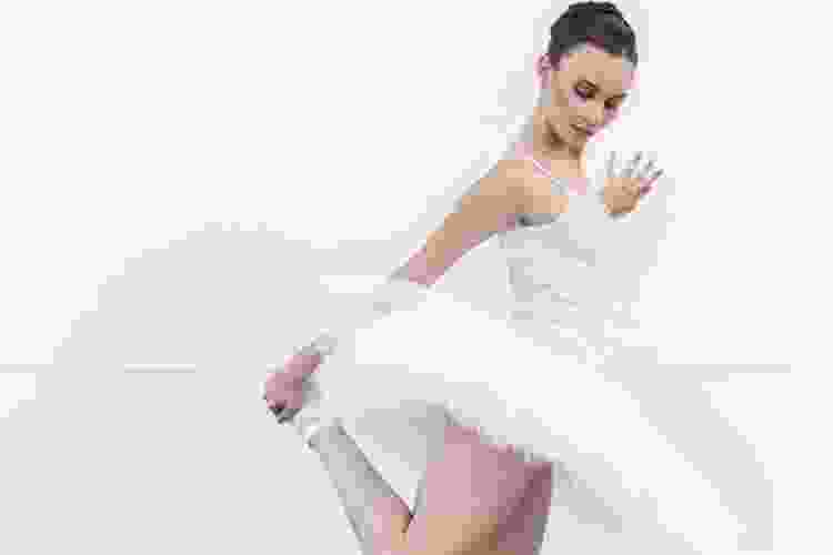 ballerina in white tutu doing hamstring stretch