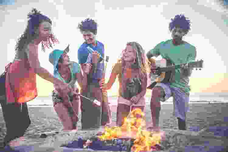 friends enjoying sunset bonfire on beach