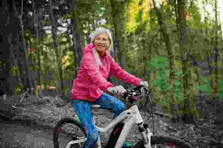 older woman riding bike in the woods