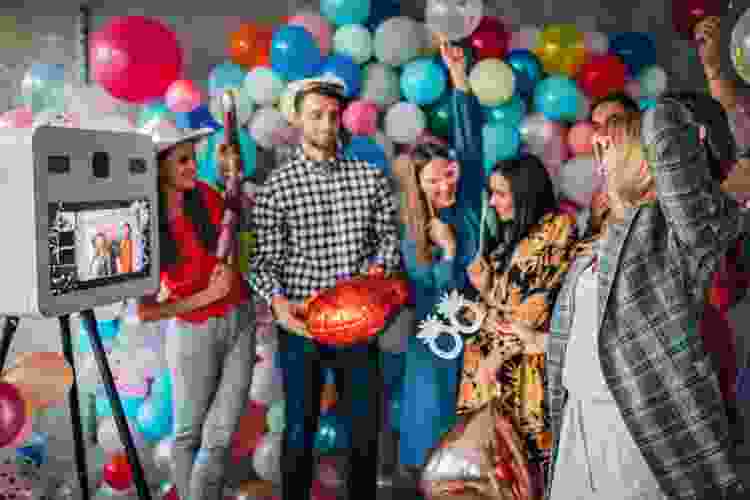 friends taking photos at photo booth surrounded by colorful balloons