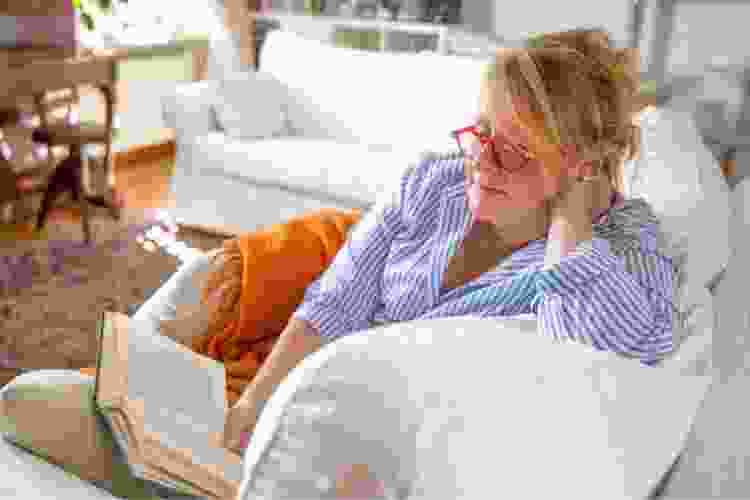 woman reading book on couch