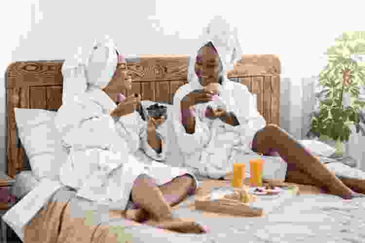 two women eating breakfast in bed together