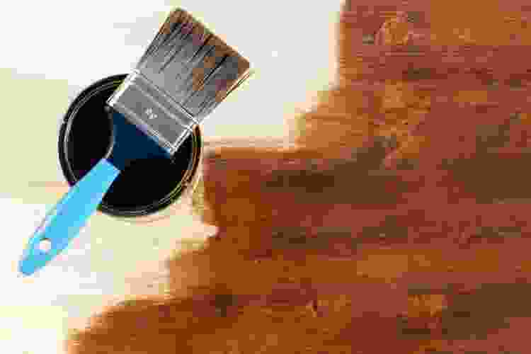 wide paint brush in bucket of dark brown paint