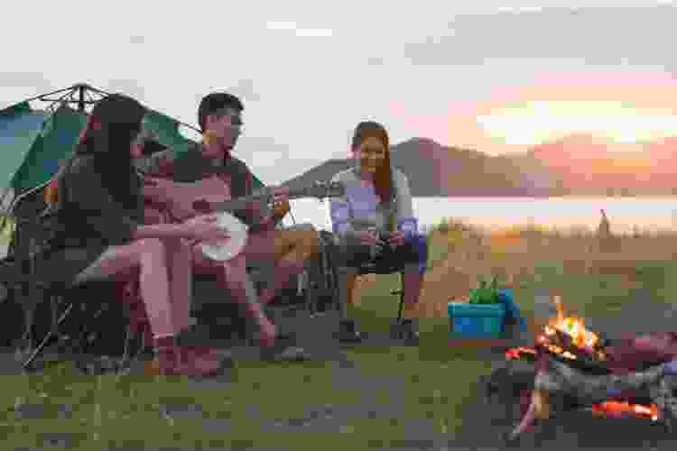 group of friends camping and playing instruments