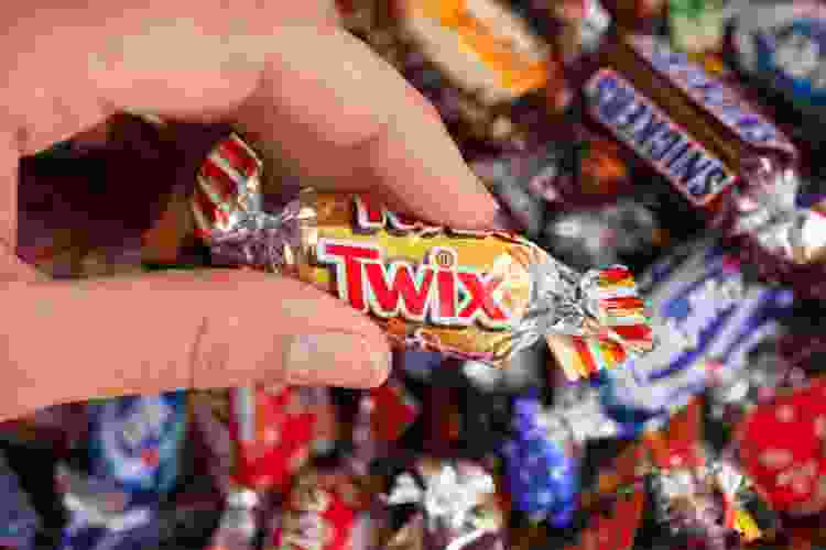 hand holding twix in a bowl of candy