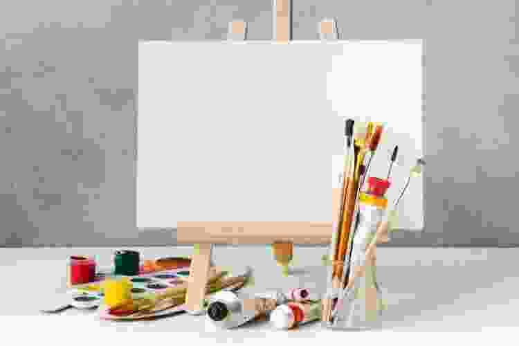 blank canvas on easel, paints and paintbrushes