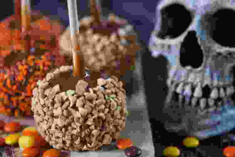 caramel apples with nuts in front of skull decoration