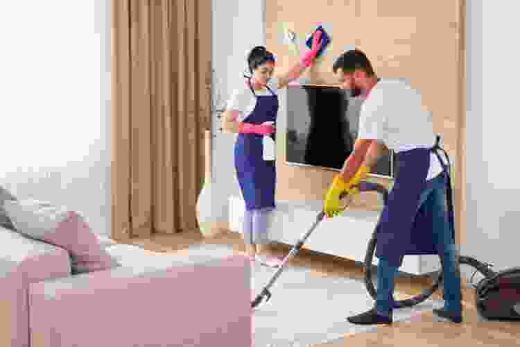 two people cleaning house with vacuum and duster