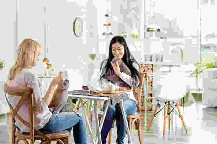 two women holding cats in  a coffee shop