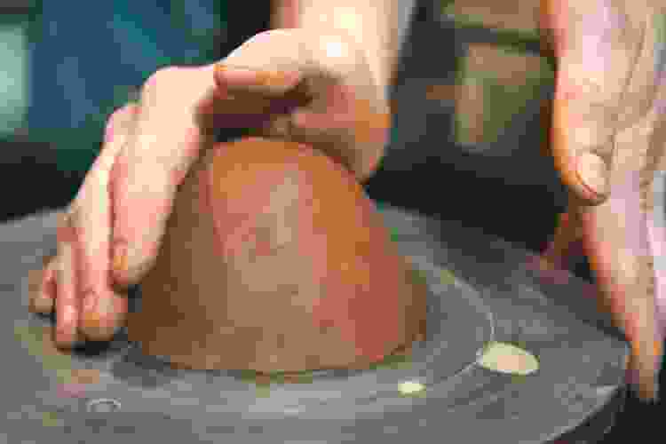 centering a slab of clay on pottery wheel 