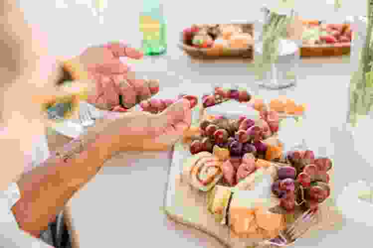 hand holding charcuterie board of cheese and snacks