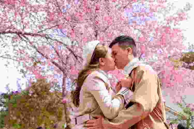 couple kissing under pink cherry blossoms