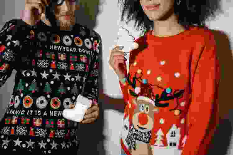 two people dressed in tacky Christmas sweaters