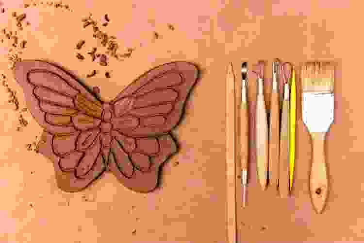 clay butterfly next to set of clay carving tools