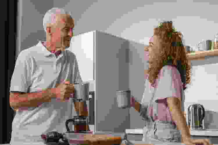 grandpa drinking coffee with granddaughter in kitchen