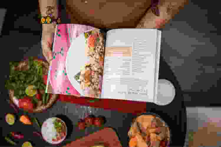 person flipping through pages of cookbook in kitchen