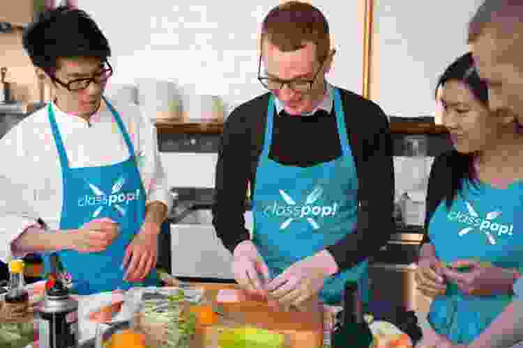 group of friends making sushi in cooking class