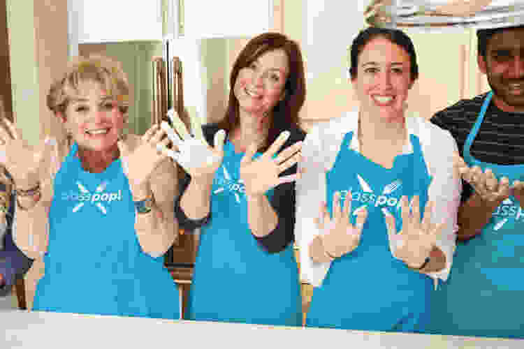 group holding flour-covered hands up in cooking class