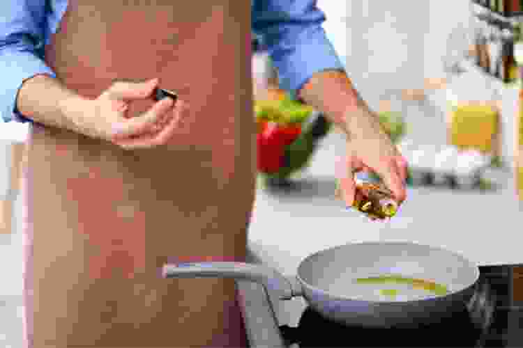 man in apron cooking in skillet