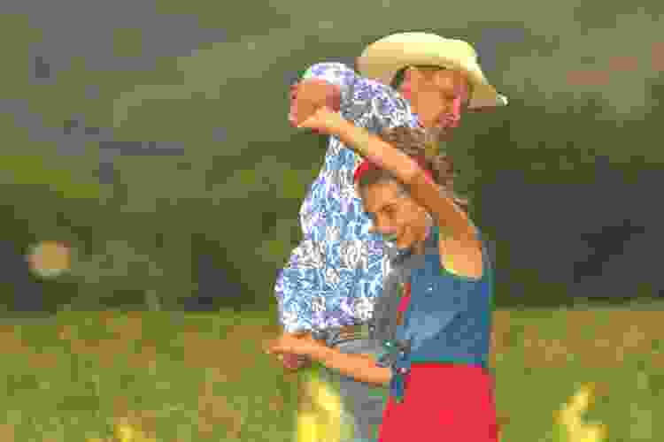 father and daughter dancing in field