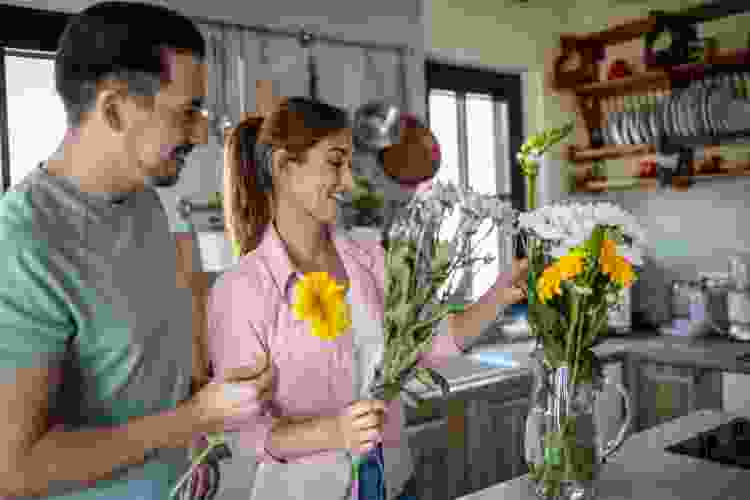 couple arranging flowers in kitchen