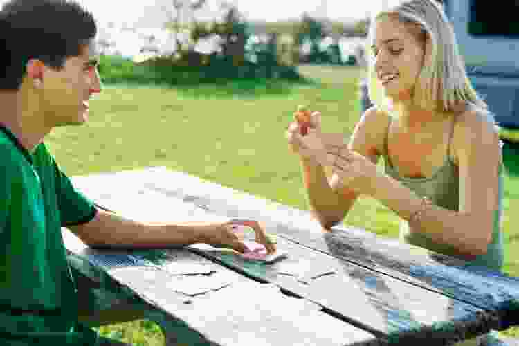 couple playing cards at picnic table