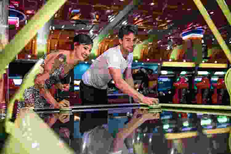 couple playing air hockey at arcade